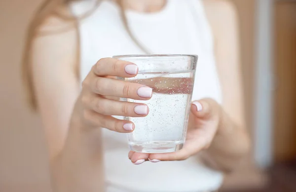 Manos femeninas sosteniendo un vaso de agua transparente. Un vaso de agua mineral limpia en las manos, bebida saludable . —  Fotos de Stock