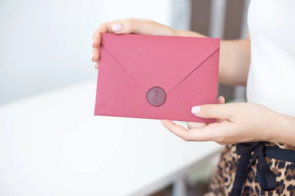 Foto de close-up de mãos femininas segurando um envelope de convite de prata com um selo de cera, um certificado de presente, um cartão postal, um cartão de convite de casamento . — Fotografia de Stock