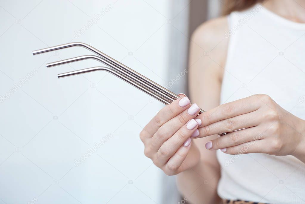 Girl is holding stainless steel straws to reduce the amount of plastic waste in the environmen.