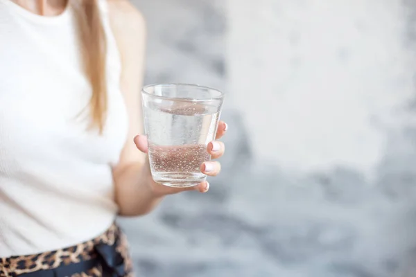 Close-up woman with slim body holding a glass of water, rear veaw. — Stock Photo, Image