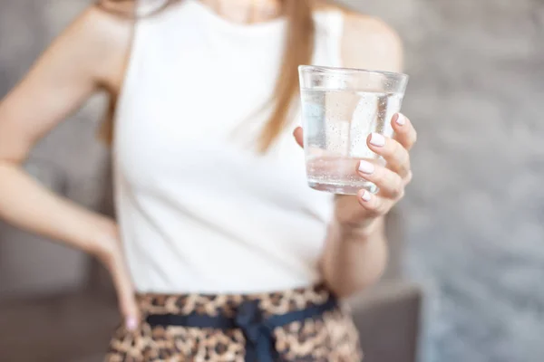 Close-up woman with slim body holding a glass of water, rear veaw. — Stock Photo, Image