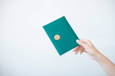 Balmumu mührü, hediye çeki, kartpostal, düğün davetiyekartı ile yeşil davetiye zarfı tutan kadın ellerinin yakın çekim fotoğrafı.