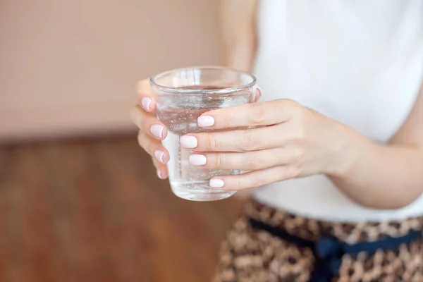 Female hands holding a clear glass of water.A glass of clean mineral water in hands, healthy drink. — Stock Photo, Image