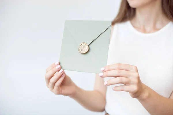 Foto de close-up de mãos femininas segurando envelope convite com um selo de cera, um certificado de presente, um cartão postal, um cartão de convite de casamento . — Fotografia de Stock