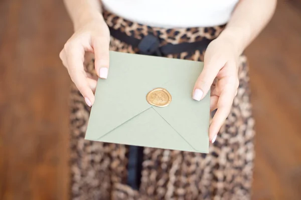 Foto de close-up de mãos femininas segurando um envelope de convite azul ou rosa prateado com um selo de cera, um certificado de presente, um cartão postal, um cartão de convite de casamento . — Fotografia de Stock