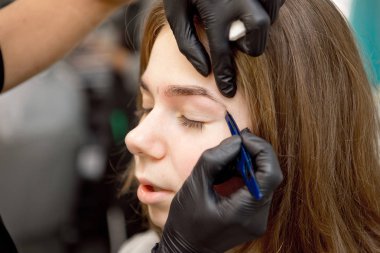 Makyaj sanatçısı güzellik stüdyosunda ayna yakınında genç kadının profesyonel makyaj yapıyor