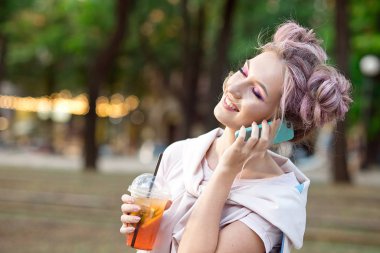 Pembe saçlı mutlu neşeli genç sarışın, şehrin arka planında yürür, arkadaşlarına bir cep telefonu yla çağırır. Sarışın öğrenci arkadaşlarıyla tanışmak için üniversiteden sonra sokakta dinleniyor