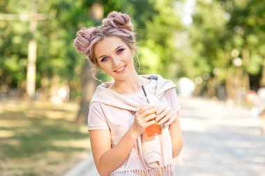 Genç güzel kız açık havada bir yürüyüşe sonra Plastik paket gıda bardak taze meyve içme. Sağlıklı bir yaşam tarzı. Pembe saç ile gülümseyen ince sarışın