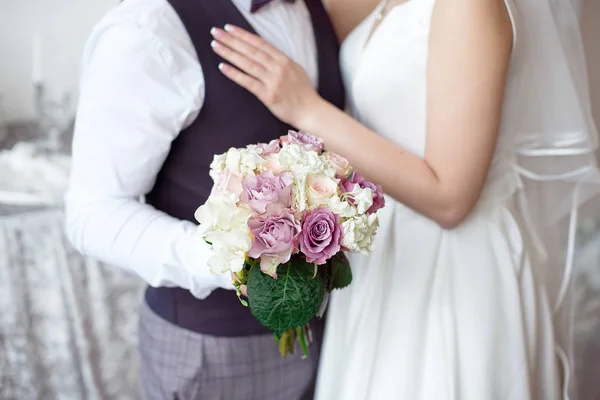 Le mani degli sposi con fedi nuziali e un mazzo di fiori — Foto Stock