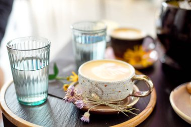 Beyaz altın ile kahve bardağı çiçek siyah bir tepsi ile bir daire üzerinde duruyor. Düz yatma.