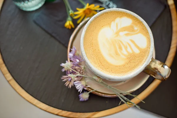 Tasse à café avec or blanc se tient sur une soucoupe avec un plateau noir de fleurs. Pose plate . — Photo