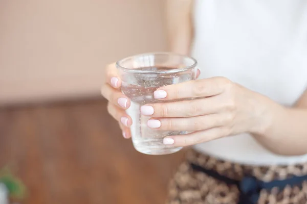 Mãos femininas segurando um copo transparente de água.Um copo de água mineral limpa nas mãos, bebida saudável . — Fotografia de Stock