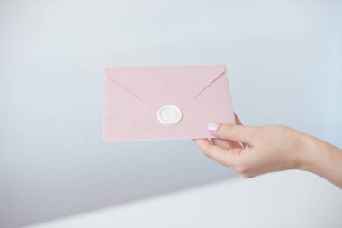 Bir balmumu mühür, bir hediye belgesi, bir kartpostal, düğün daveti ile davet zarf tutan kadın elleri yakın çekim fotoğrafı