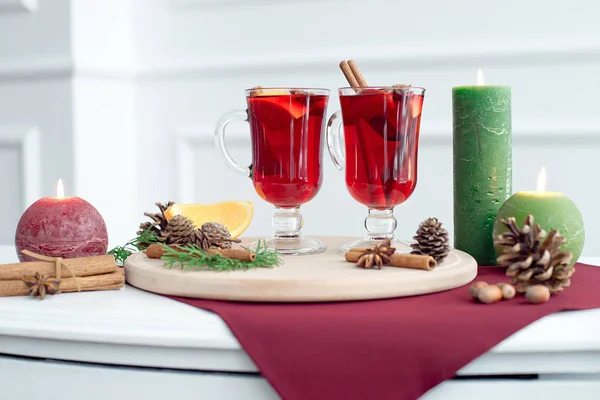 Christmas hot mulled wine with cinnamon, cardamom and anise on a white wooden background. Christmas table with hot drink, candles and wooden tray — Stock Photo, Image