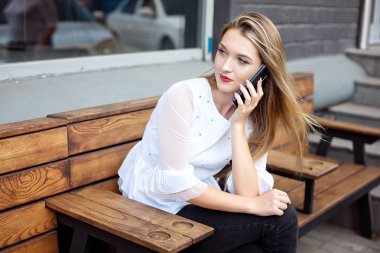 Güzel bir gülümseme ile Charming kadın bir kafede dinlenirken bir cep telefonu iyi haber konuşuyor, mutlu bir Kafkas kadın boş zamanlarında bir kafede dinlenirken bir cep telefonu konuşuyor.