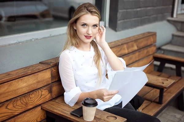 Mulher lendo um documento enquanto estava sentada em um café, desfrutando de uma xícara de café da manhã, vista de perto de suas mãos . — Fotografia de Stock