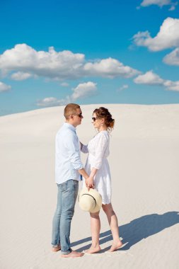 Genç çift kum tepelerinde gün batımının tadını çıkarıyor. Romantik gezgin çölde yürür. Macera seyahat yaşam tarzı kavramı