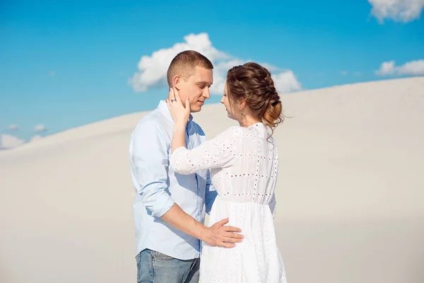 Fiatal férfi és nő ölelgetés a háttérben a fehér homok, dűnék. Szerelmi történet az üresség. — Stock Fotó