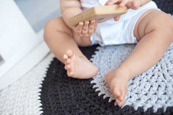 Bambino carino in tuta blu si siede su un tappeto lavorato a maglia . — Foto Stock