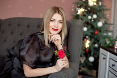 Mutlu yıllar sana. Siyah bir elbise ve parlak makyaj Yeni Yıl çelenk arka planda Noel kutlayan bir güzel genç kadın. Yeni yıl partisi. Noel Arifesi