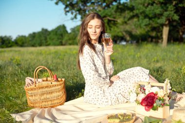 Güneşli havalarda dekore edilmiş akşam yemeği yeri ile bahçede yemek sepeti ile ayakta genç bir güzel kadın Portresi.