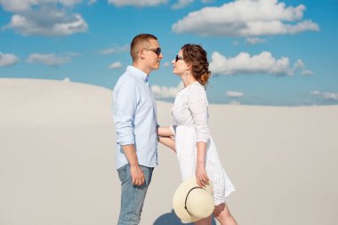 Genç çift kum tepelerinde gün batımının tadını çıkarıyor. Romantik gezgin çölde yürür. Macera seyahat yaşam tarzı kavramı