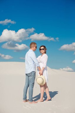 Genç çift kum tepelerinde gün batımının tadını çıkarıyor. Romantik gezgin çölde yürür. Macera seyahat yaşam tarzı kavramı