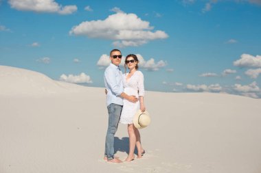 Genç çift kum tepelerinde gün batımının tadını çıkarıyor. Romantik gezgin çölde yürür. Macera seyahat yaşam tarzı kavramı