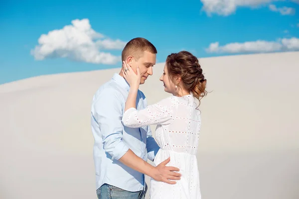 Zdjęcie wspaniałej pary mężczyzny i kobiety uśmiechając się i przytulając na piaszczystym wzgórzu na tle błękitnego nieba i białych chmur. — Zdjęcie stockowe