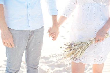 El ele tutuşan kum tepelerinde gün batımının tadını çıkaran genç bir çiftin yakın çekim. Romantik gezgin çölde yürür. Macera seyahat yaşam tarzı kavramı