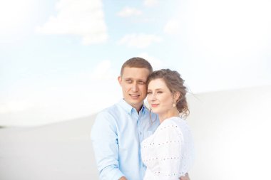 Genç adam ve kadın beyaz kum, kumulbir arka plan üzerinde sarılma. Boşlukta aşk hikayesi.