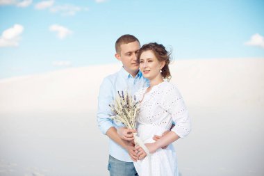 Genç adam ve kadın beyaz kum, kumulbir arka plan üzerinde sarılma. Boşlukta aşk hikayesi.