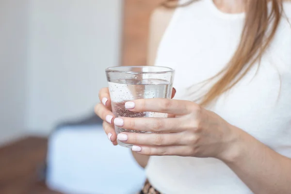 Mãos femininas segurando um copo transparente de água.Um copo de água mineral limpa nas mãos, bebida saudável — Fotografia de Stock