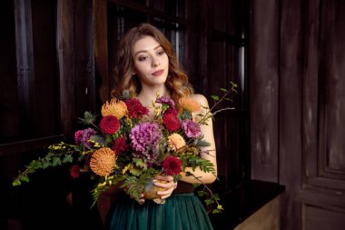 Cadılar Bayramı parti kızı. Mutlu Cadılar Bayramı güzel kız siyah bir üst ve elinde tam bir etek sonbahar çiçekleri ile bir buket tutar