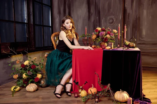 Молодая женщина готовится к Хэллоуину, накрывая стол для праздничного ужина. Красивая тыква — стоковое фото