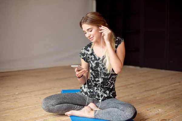 Молода жінка щаслива бере селфі під час прослуховування музики, сидячи на підлозі з телефонами . — стокове фото
