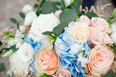 Gelin elmas alyansı ve nişan yüzüğünün yakın plan resmi. Çiçek buketine yerleştirilmiş..