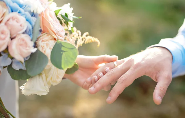 Sposa indossa sposo una fede nuziale mano sposa tiene un bellissimo bouquet da sposa — Foto Stock