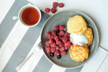 Gri bir tabakta ev yapımı peynirli kek. Küçük porsiyonlu ahududu turtası, beyaz arka plan