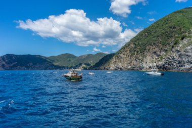 Avrupa, İtalya, Cinque Terre, Monterosso. Arka planda dağ olan bir su kütlesi içinde küçük bir tekne.