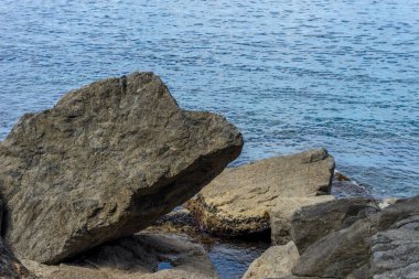 Avrupa, İtalya, Cinque Terre, Riomaggiore, bir kaya parçasının yanında oturan bir adam.