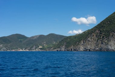 Avrupa, İtalya, Cinque Terre, Riomaggiore, arkasında dağ olan büyük bir su kütlesi.