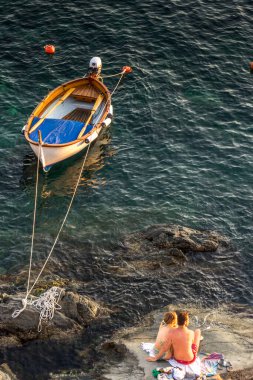 Riomaggiore, Cinque Terre, İtalya - 26 Haziran 2018: Okyanusu aşan Riomaggiore 'da günbatımını seyreden turist balayı çifti