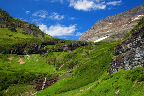 Hierba verde y cascadas a lo largo de la carretera Going to the Sun en el Parque Nacional Glaciar — Foto de Stock