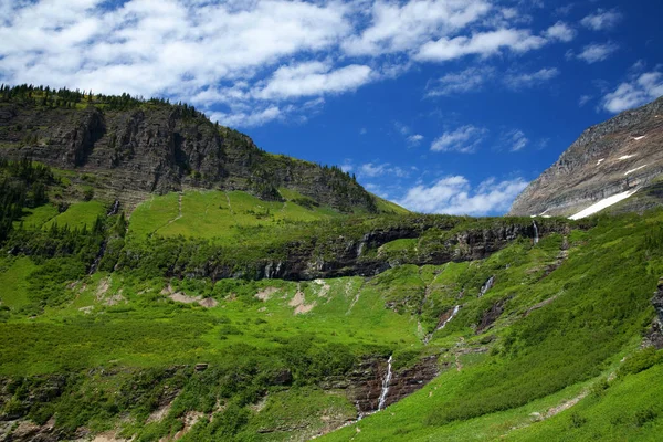 Hierba verde y cascadas a lo largo de la carretera Going to the Sun en el Parque Nacional Glaciar — Foto de Stock