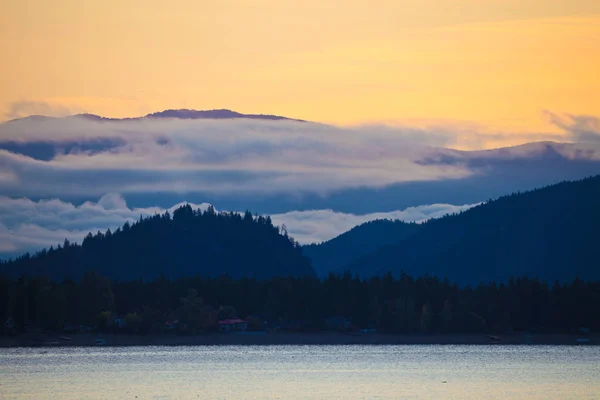Colline sagomate intorno al lago Shuswap e cielo colorato arancione, Columbia Britannica — Foto Stock