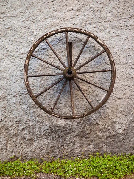 An old wagon wheel displayed on a rustic old wall