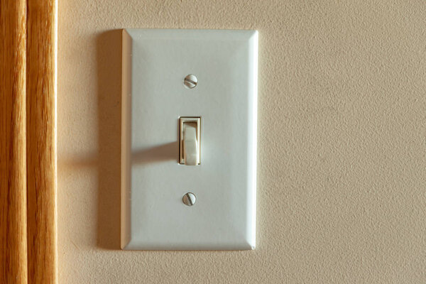 An North American light switch on a wall near a doorway