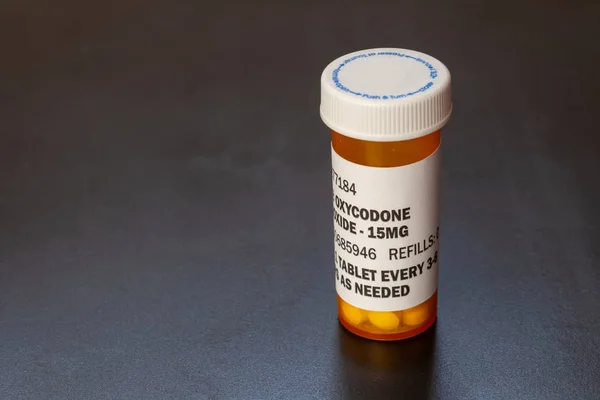 Prescription bottle with backlit Oxycodone tablets. Oxycodone is a generic prescription opioid.