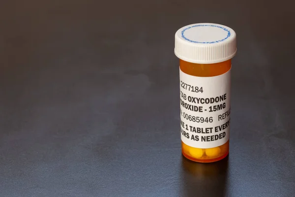 Prescription bottle with backlit Oxycodone tablets. Oxycodone is a generic prescription opioid.